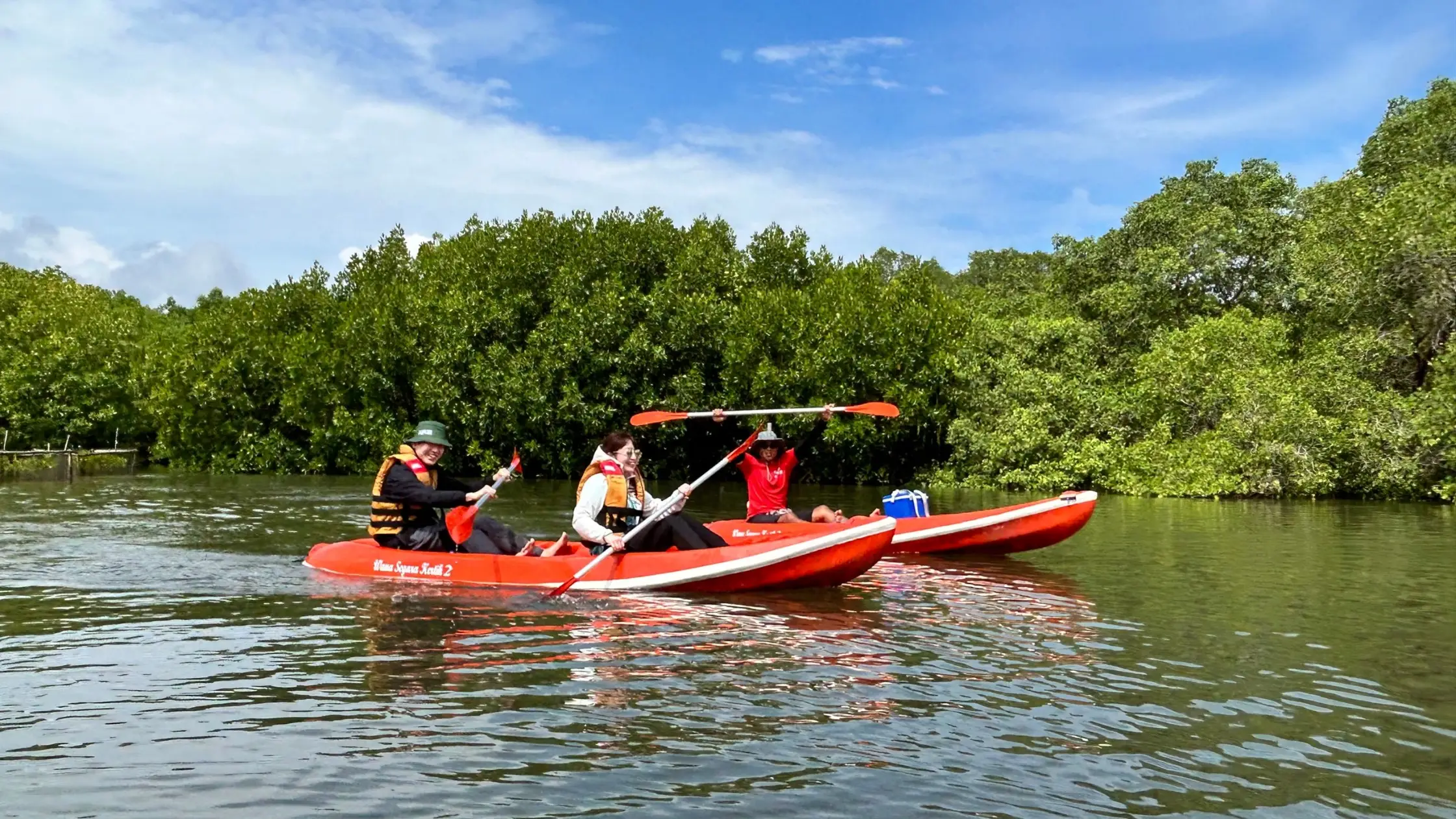 Happy travelers on red kayaks enjoying Bali Mangrove Adventure eco tour