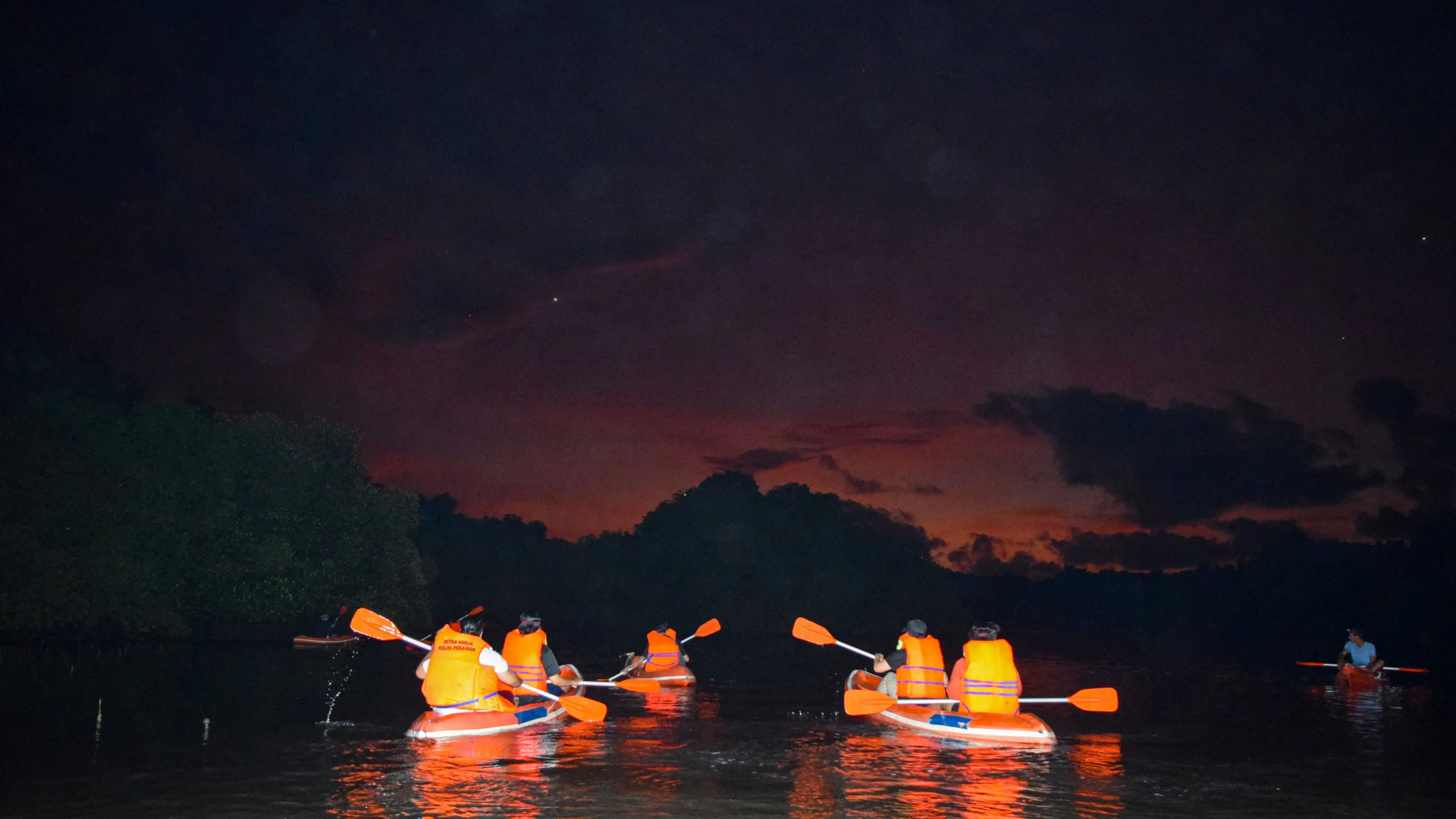 Evening mangrove canoe tour in Bali with travelers paddling under the twilight sky during a Bali night out