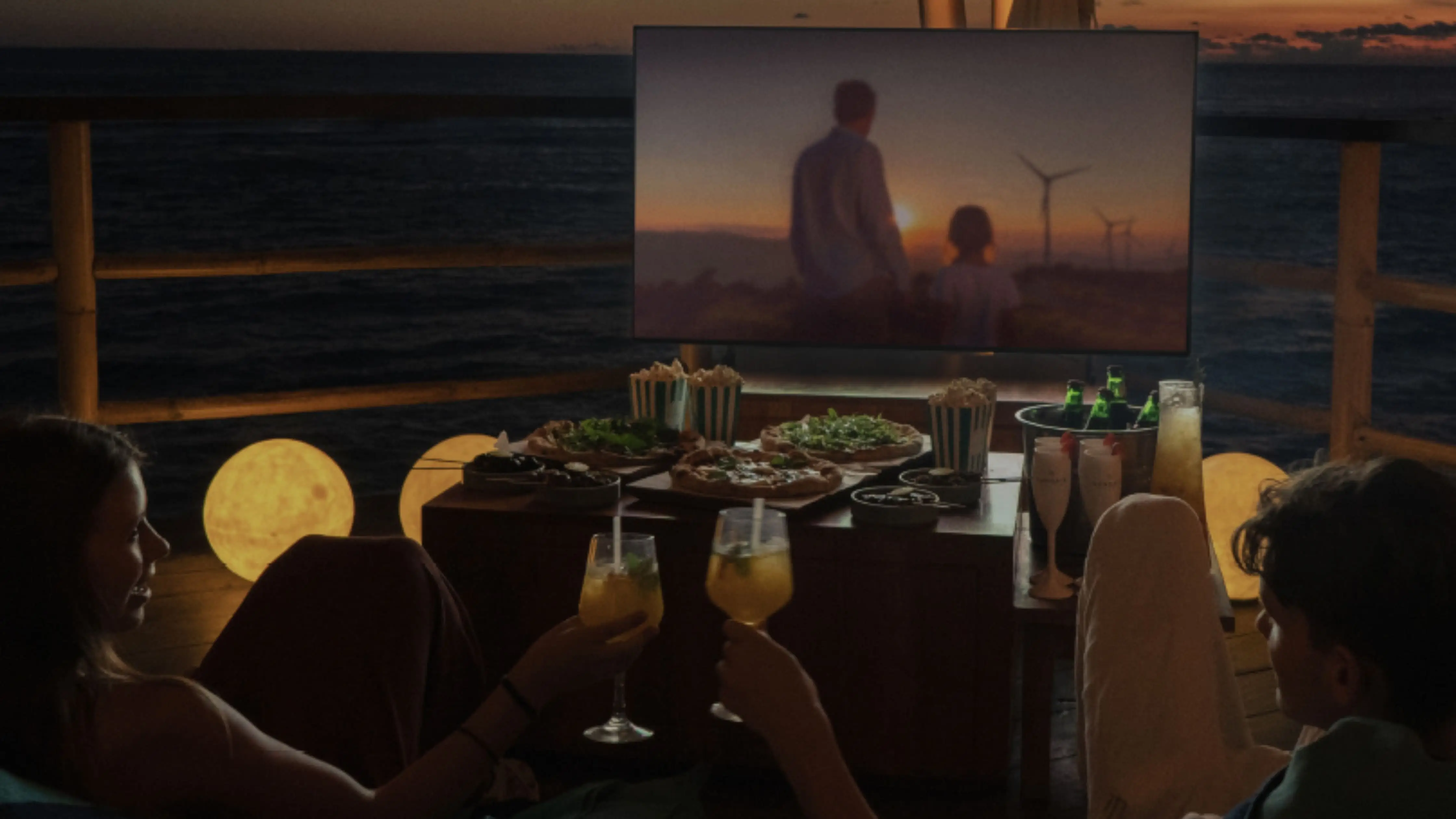 Outdoor beach cinema in Bali with a couple watching movies under a starlit beachfront sky