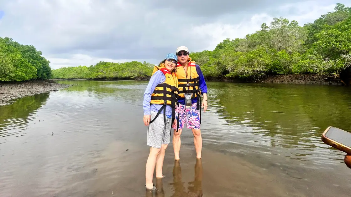 Couple wearing life jackets standing in shallow mangrove water