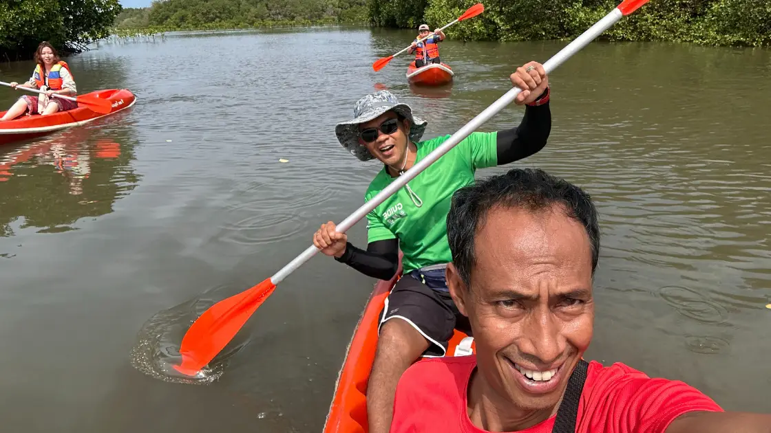 Friendly Bali Mangrove Adventure guides leading guests on a canoeing tour through the mangrove forest, smiling and paddling together